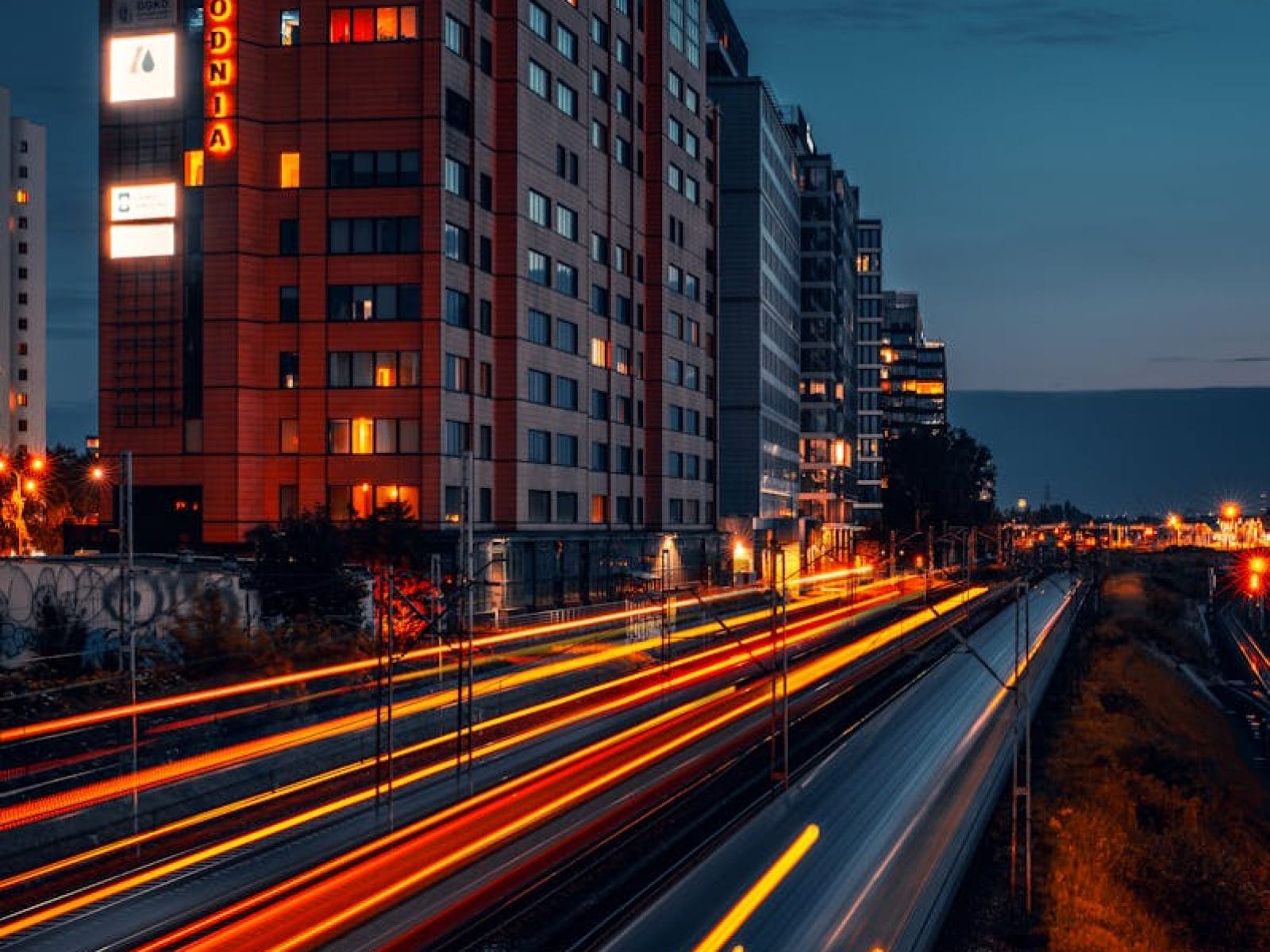 Dynamic night scene of Warsaw cityscape featuring light trails and modern architecture.