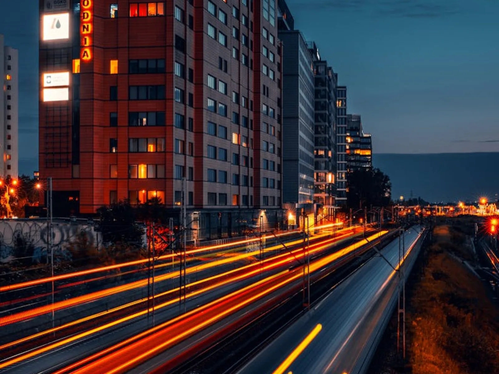 Dynamic night scene of Warsaw cityscape featuring light trails and modern architecture.