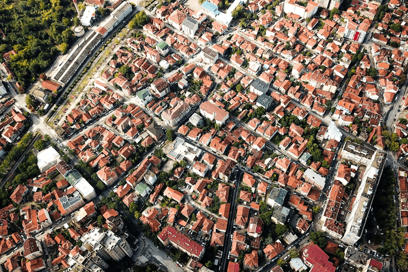 Aerial shot showcasing city blocks with distinct red-roofed buildings and greenery.