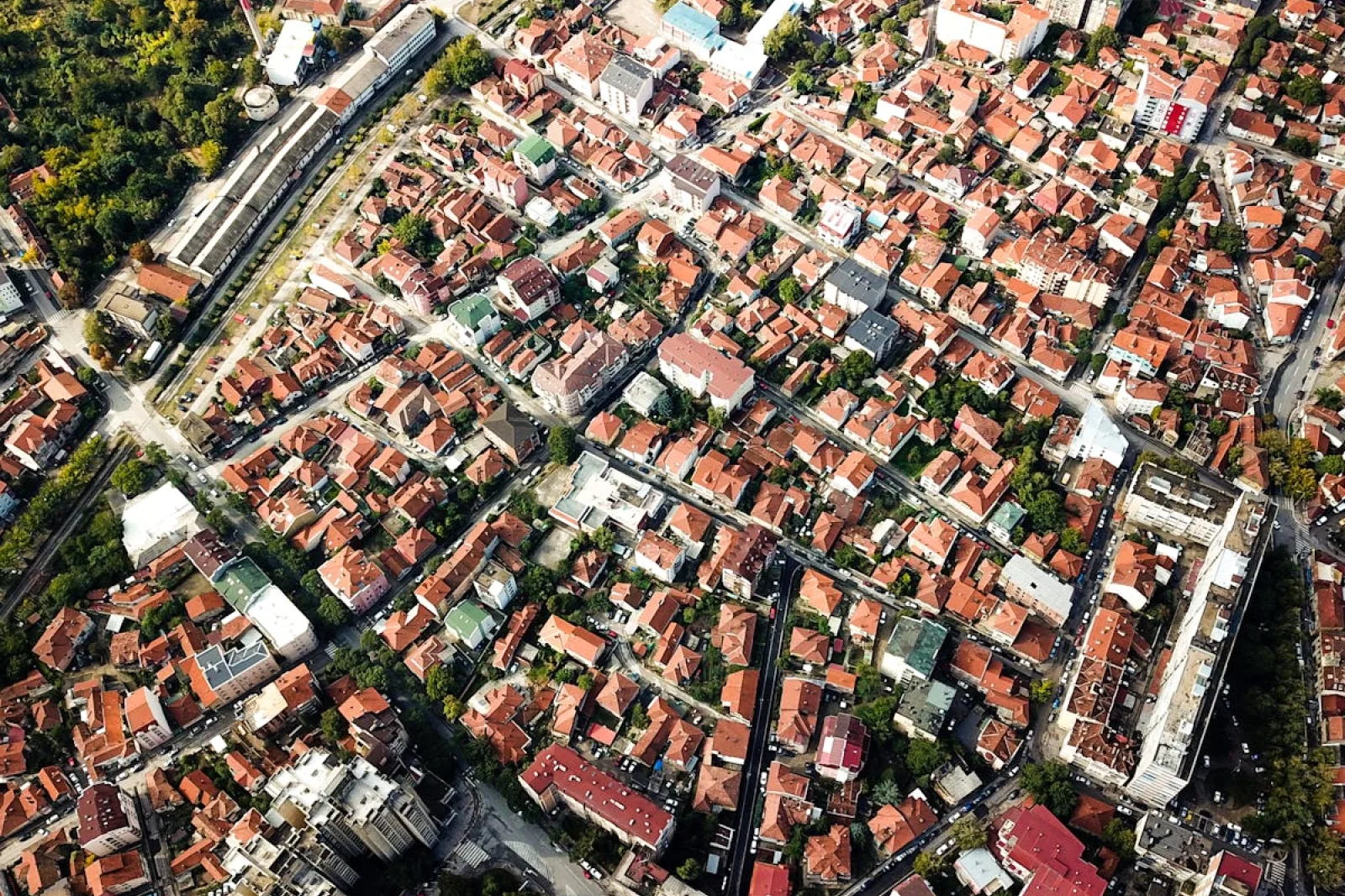 Aerial shot showcasing city blocks with distinct red-roofed buildings and greenery.