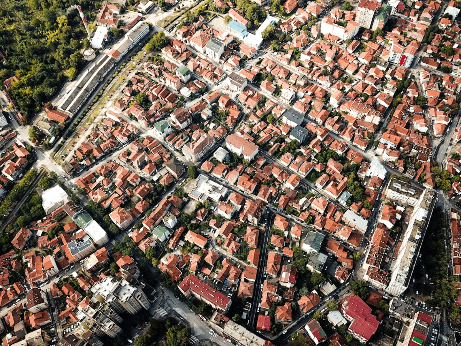 Aerial shot showcasing city blocks with distinct red-roofed buildings and greenery.