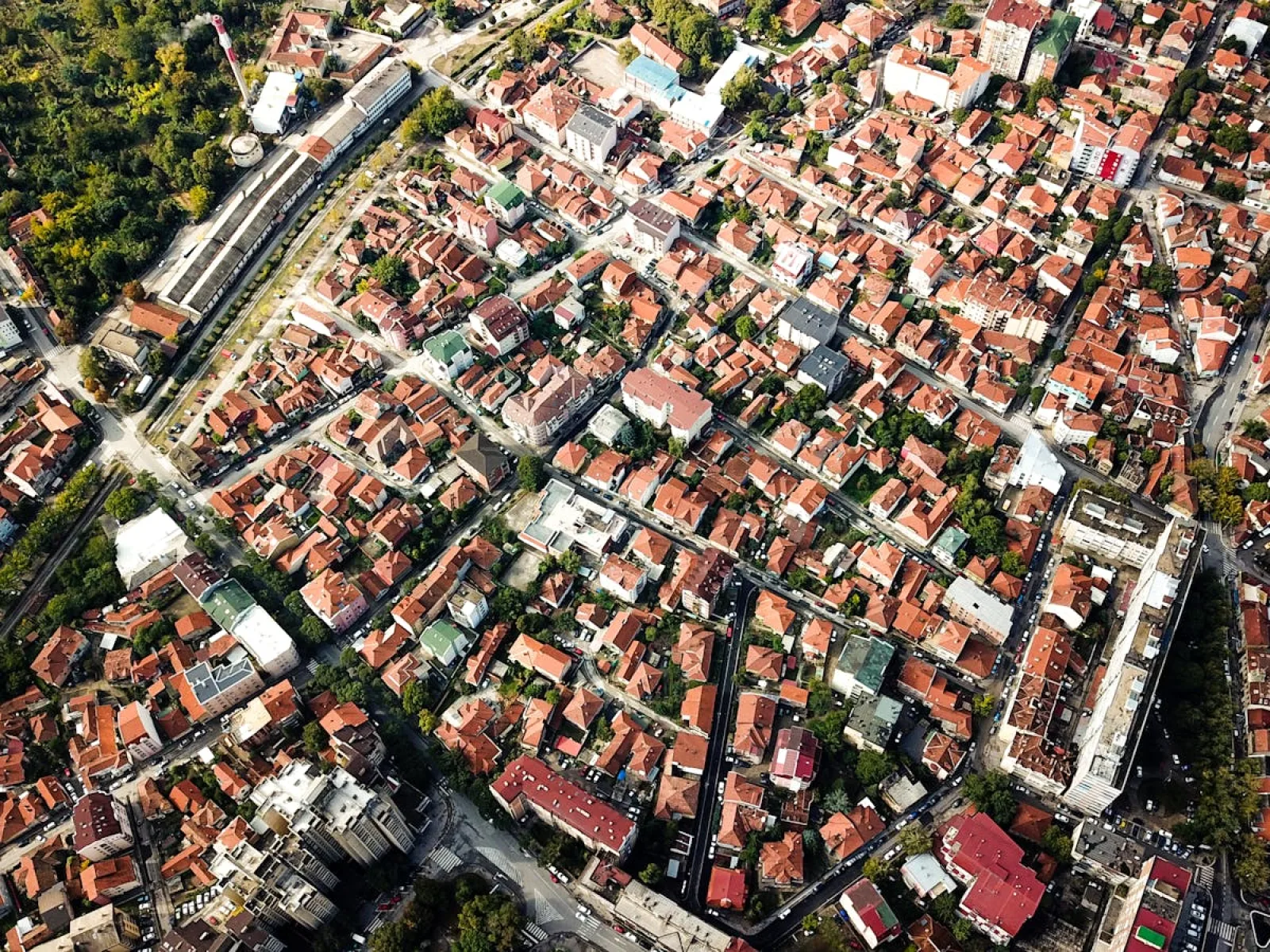 Aerial shot showcasing city blocks with distinct red-roofed buildings and greenery.