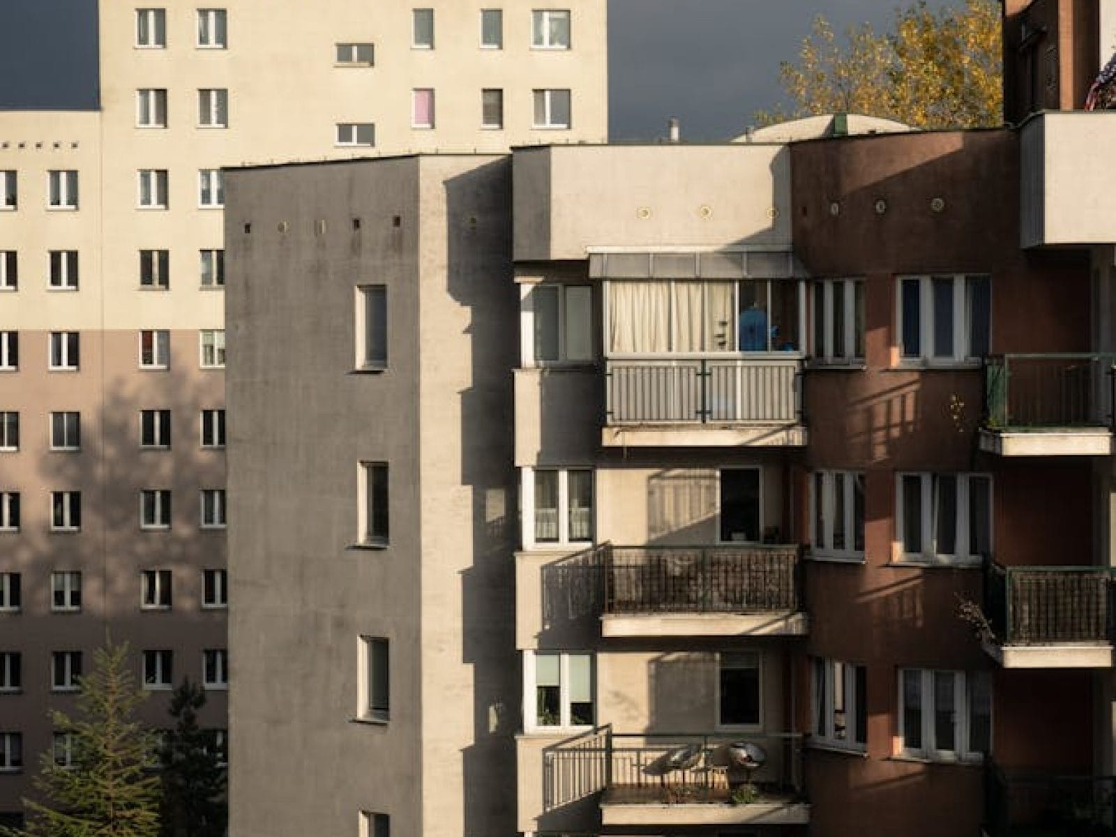Vertical shot of urban apartment buildings with balconies under dramatic sky.