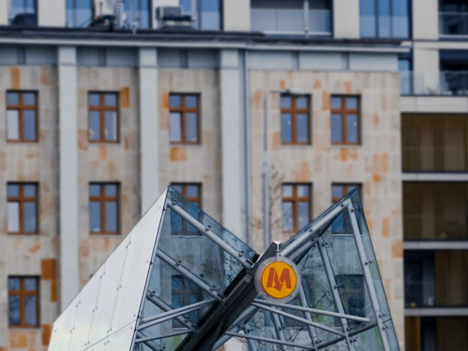 Contemporary glass entrance to Warsaw Metro with urban backdrop.