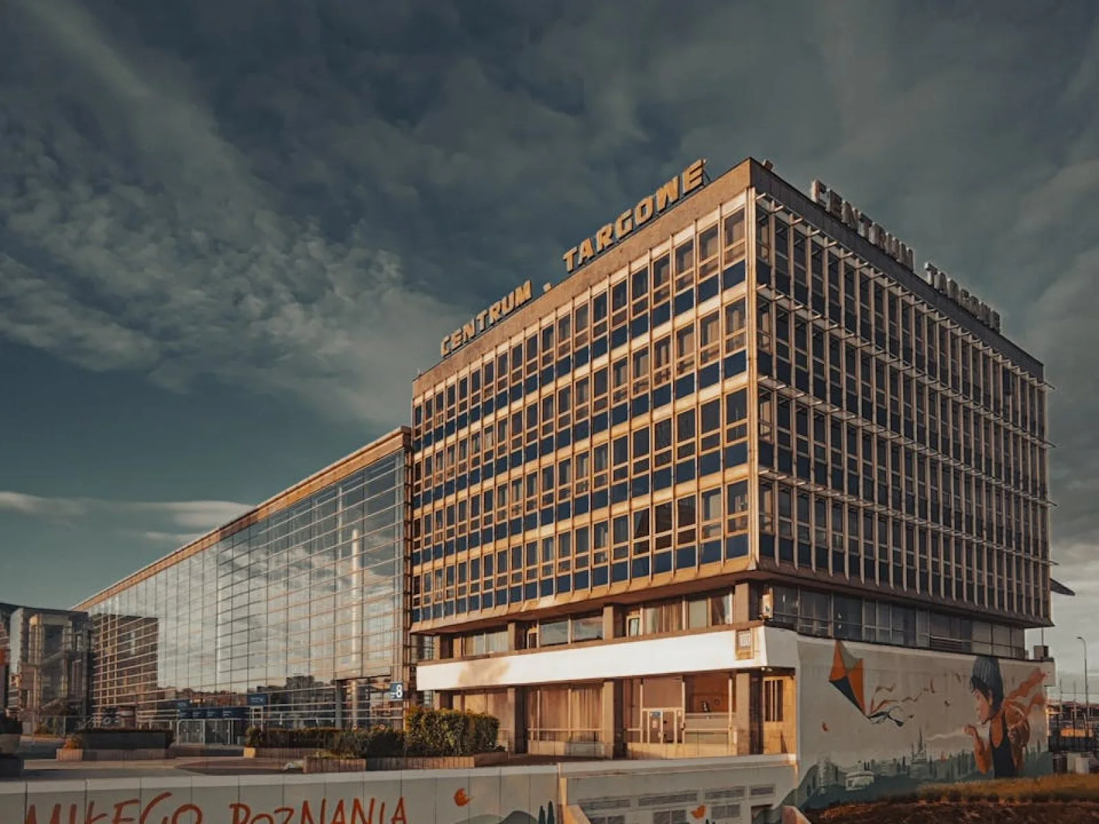 Modern building at Poznan Trade Center with dramatic skies and reflective glass facade.
