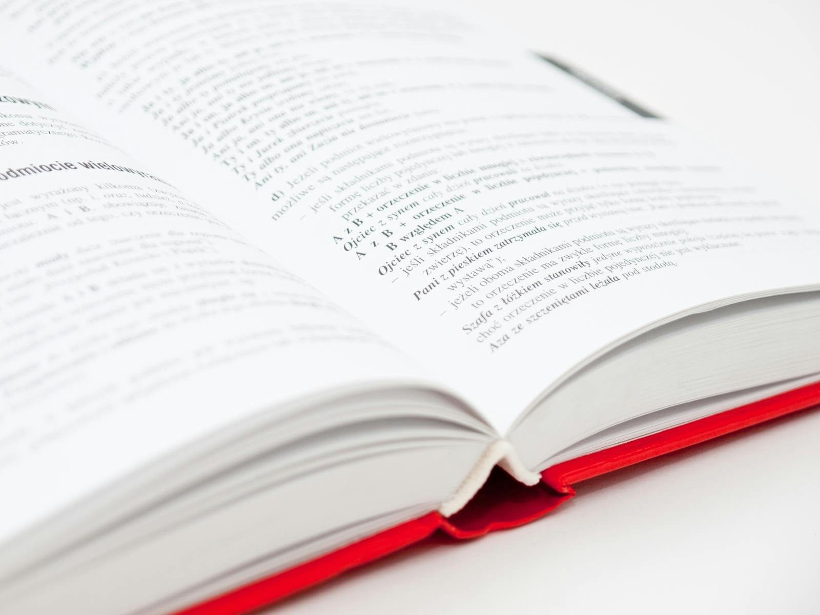 An open book with a red cover showing pages filled with text, symbolizing knowledge and education.