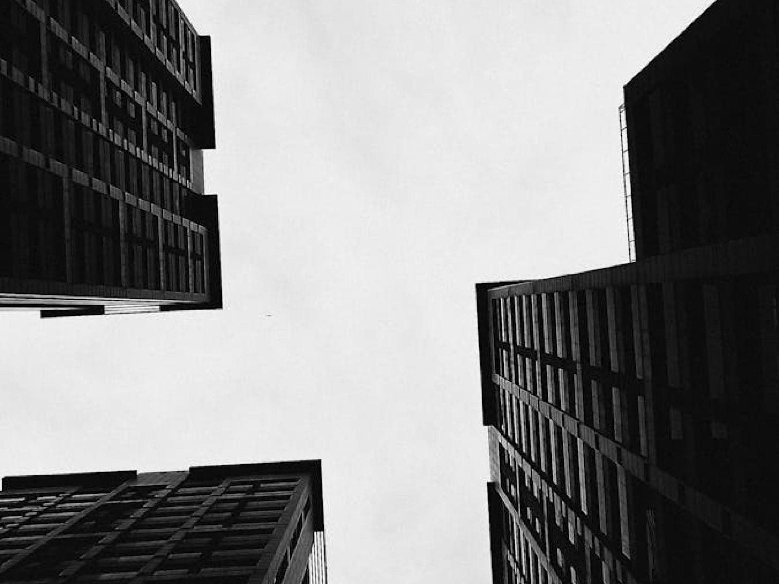A stark black and white photo capturing dramatic urban skyscrapers from below.